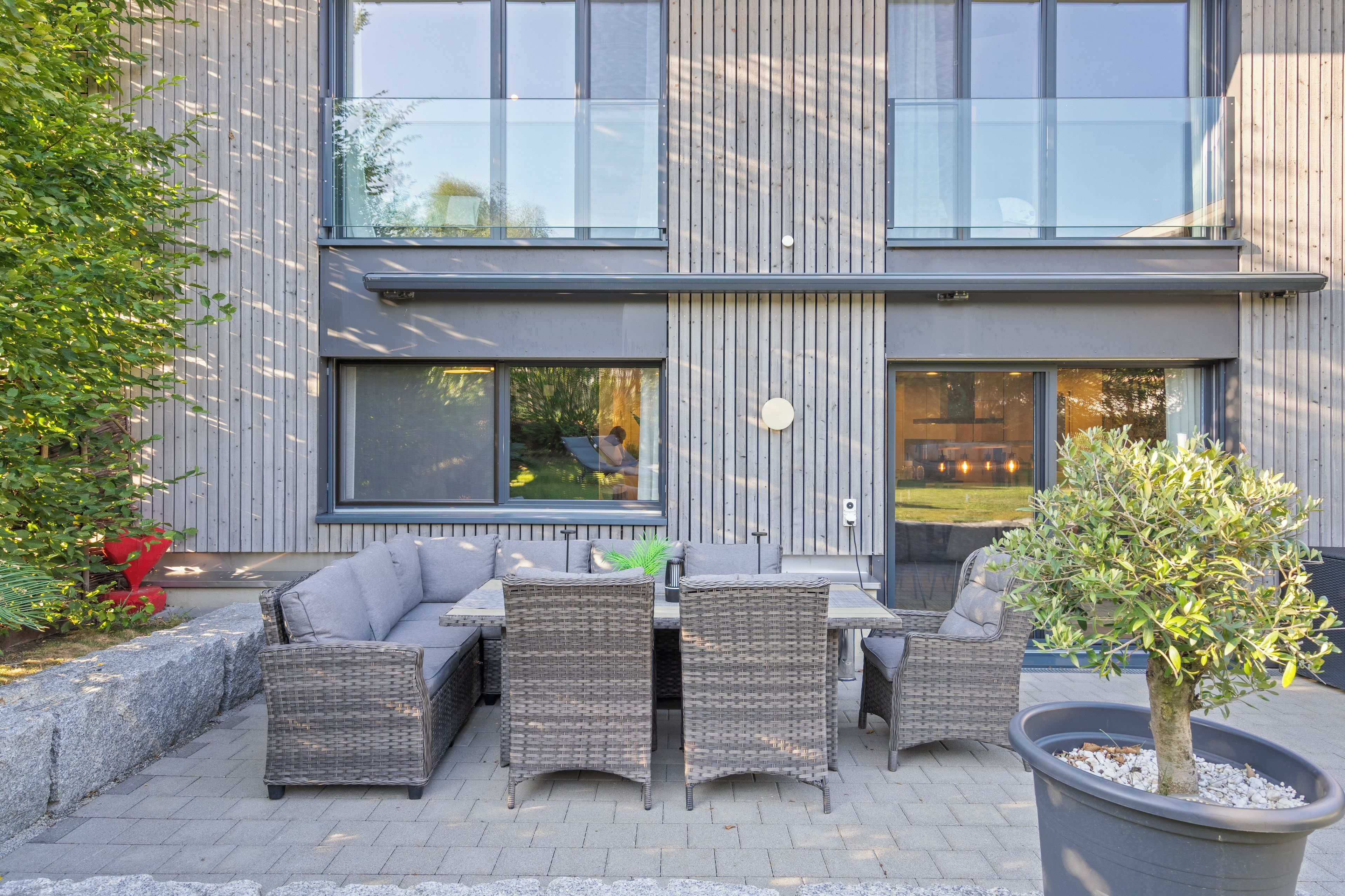 Un espace extérieur aménagé avec des meubles en osier et une plante en pot.