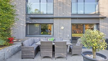 Un espace extérieur aménagé avec des meubles en osier et une plante en pot.