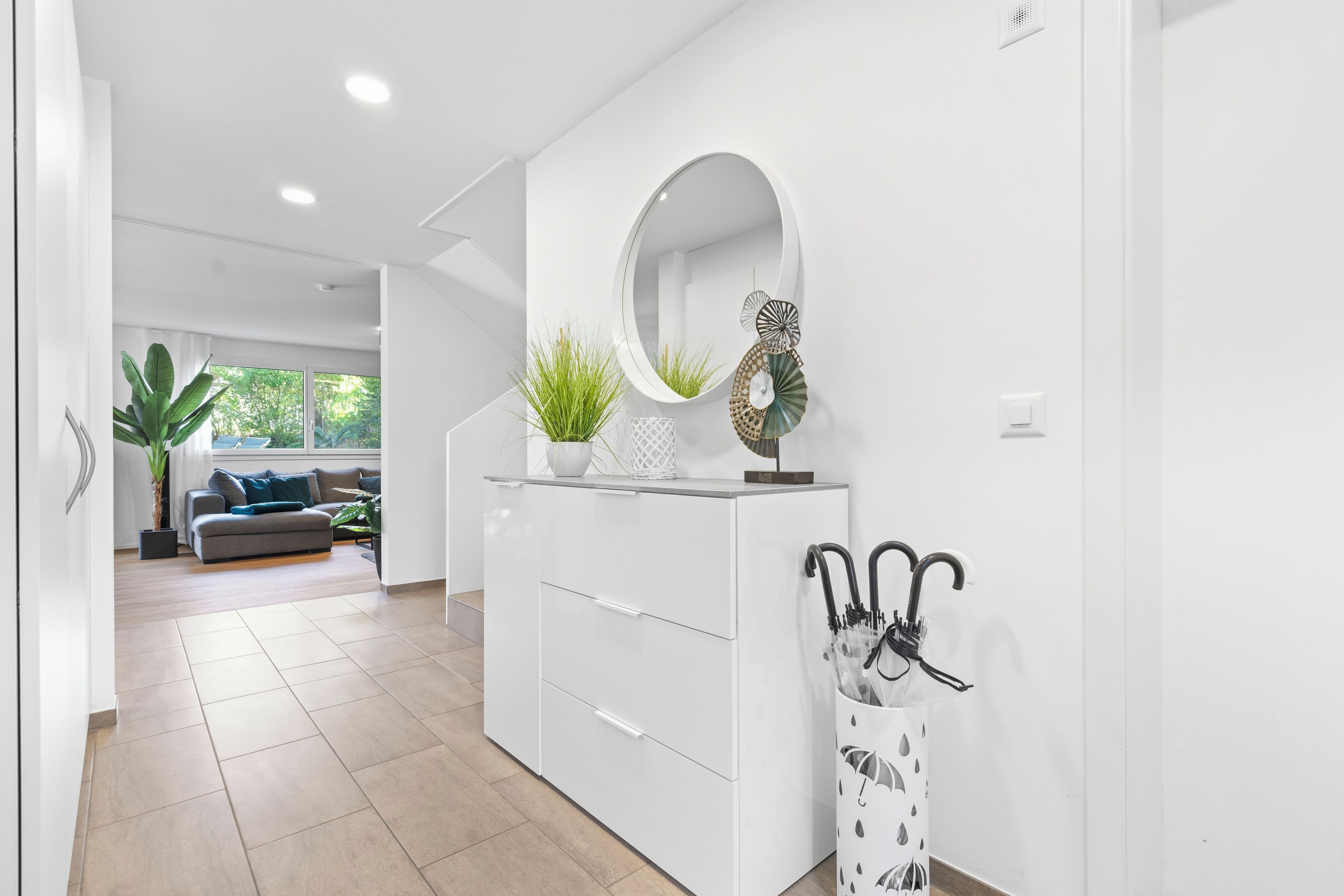 Un intérieur moderne avec une console blanche, un miroir et des plantes décoratives.