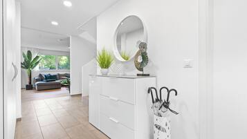 Ein modernes Interieur mit einer weißen Konsole, einem Spiegel und Zimmerpflanzen.