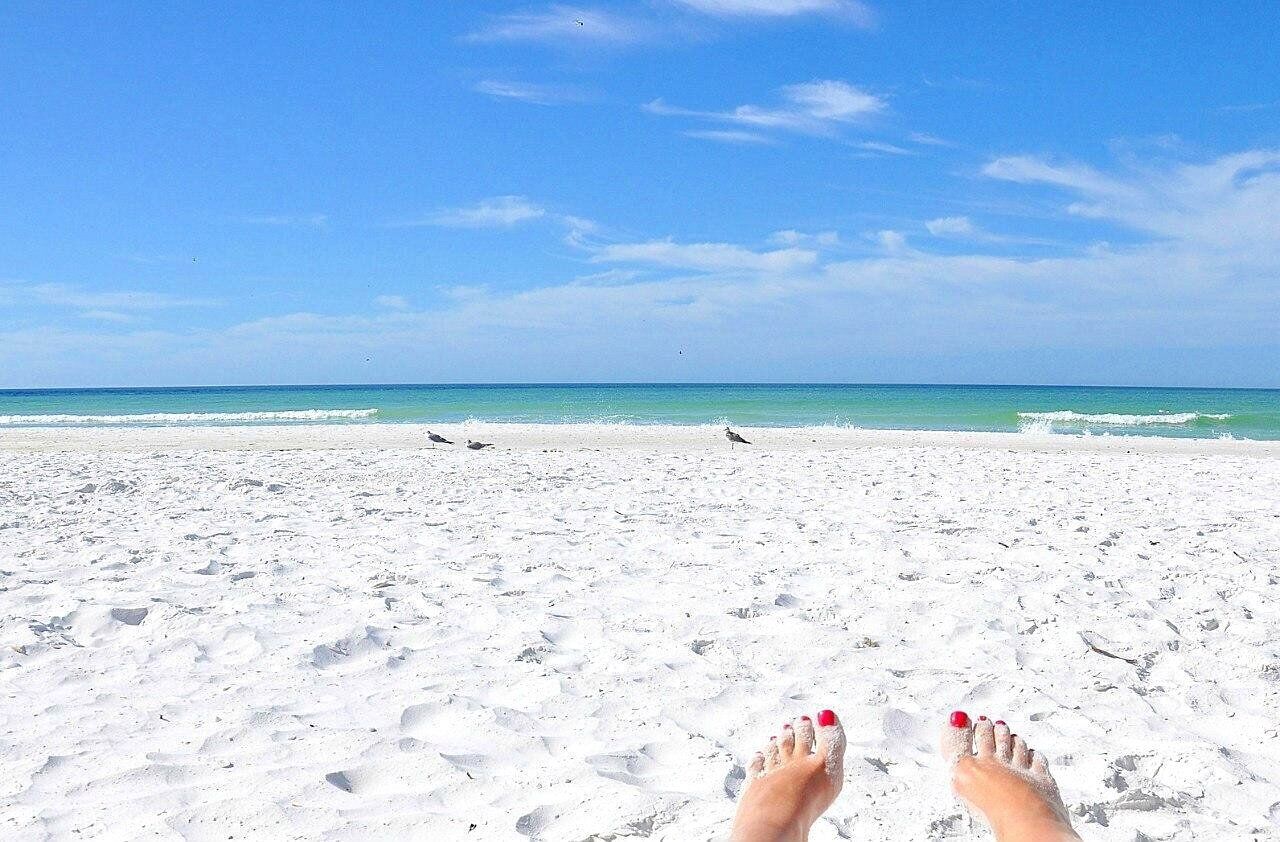 Una playa con arena blanca y cielo azul despejado.