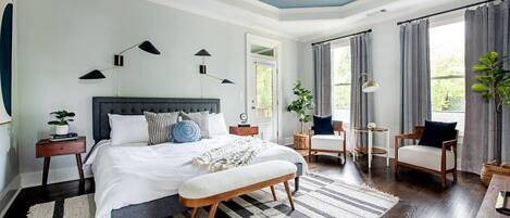 Un dormitorio con una cama grande, mesitas de noche, un banco y un ventilador de techo.