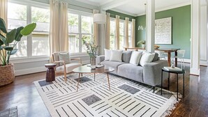 A modern living room with a grey sofa, a coffee table, and a large window with curtains.