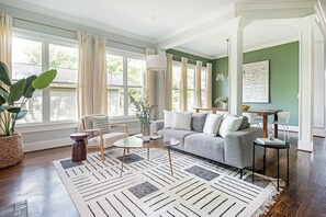 A modern living room with a grey sofa, a coffee table, and a large window with curtains.