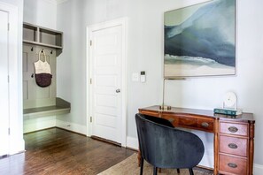 Quarto com uma escrivaninha de madeira, uma cadeira, uma estante e um quadro na parede.