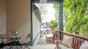 A covered patio with a wooden bench, a small table, and folding chairs.