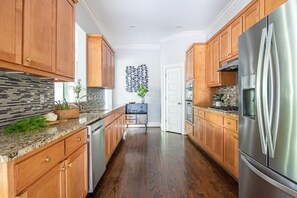 Uma cozinha com armários de madeira, geladeira de aço inoxidável e painel de azulejos.