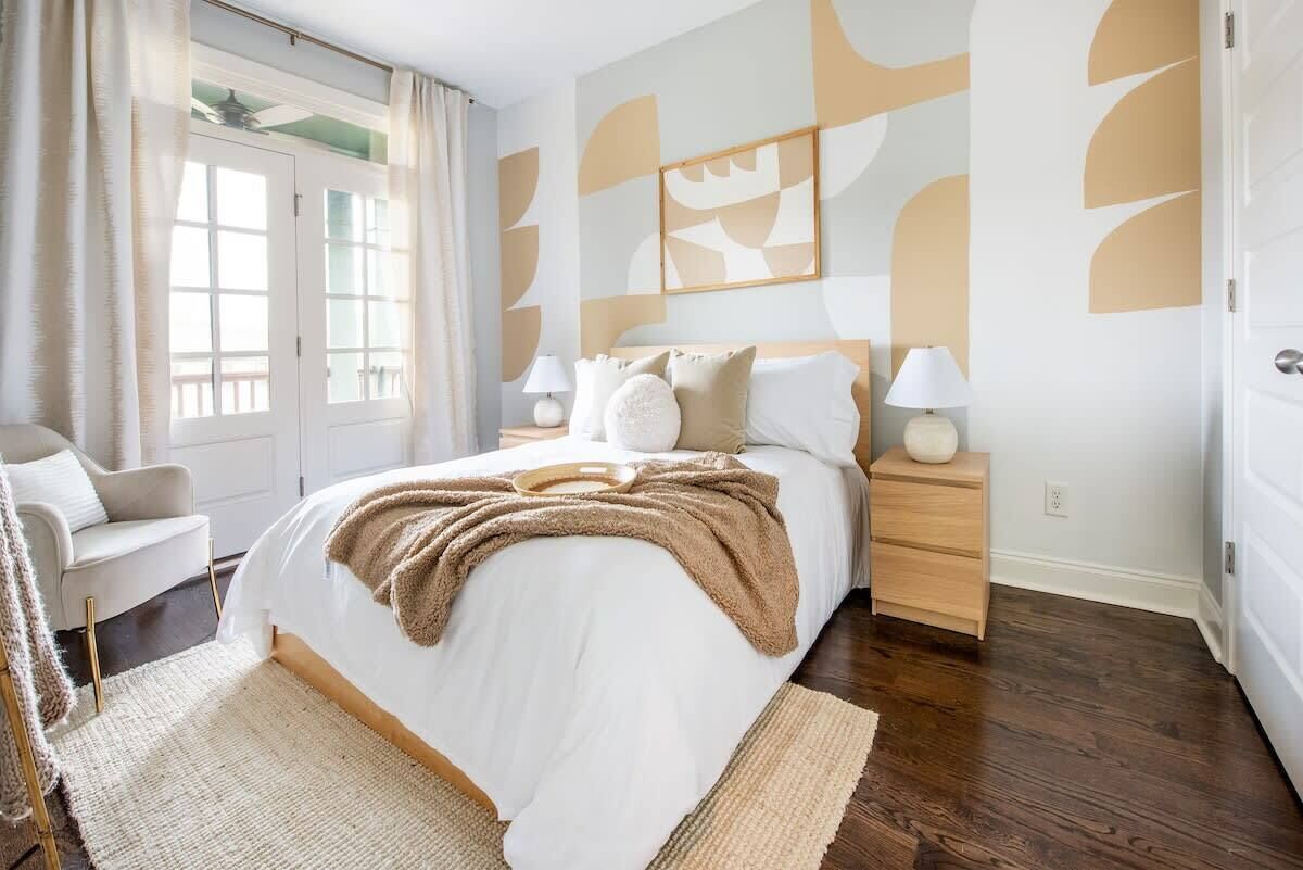 A bedroom with a large bed, bedside tables, a chair, and a window with curtains.