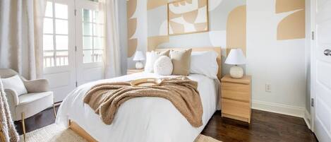 A bedroom with a large bed, bedside tables, a chair, and a window with curtains.
