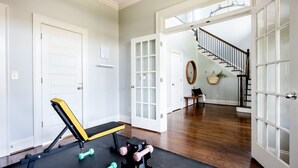 A home gym with exercise equipment, a staircase, and a view of the outside.