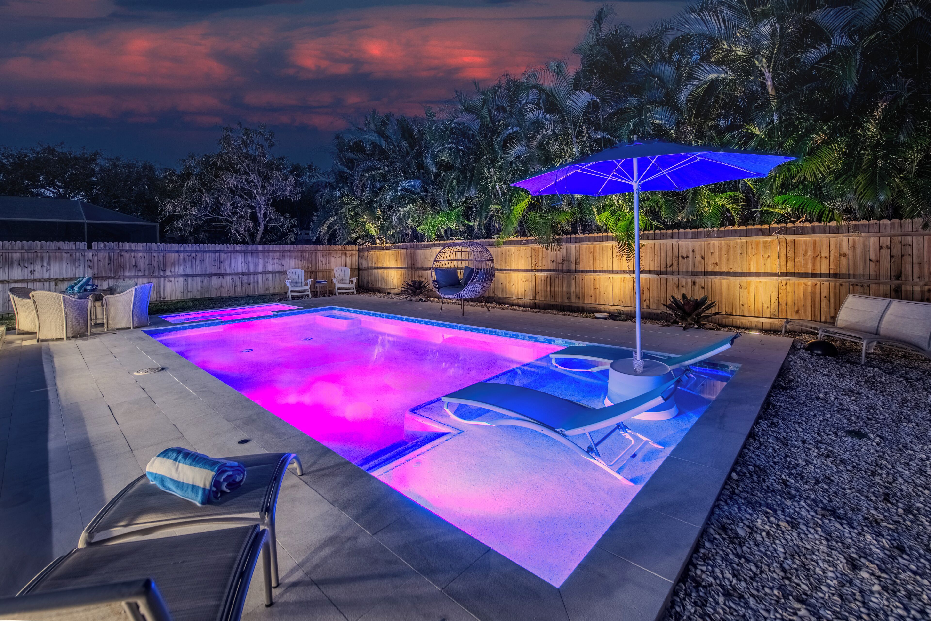 Un jardin avec une piscine, des chaises longues et un hamac.