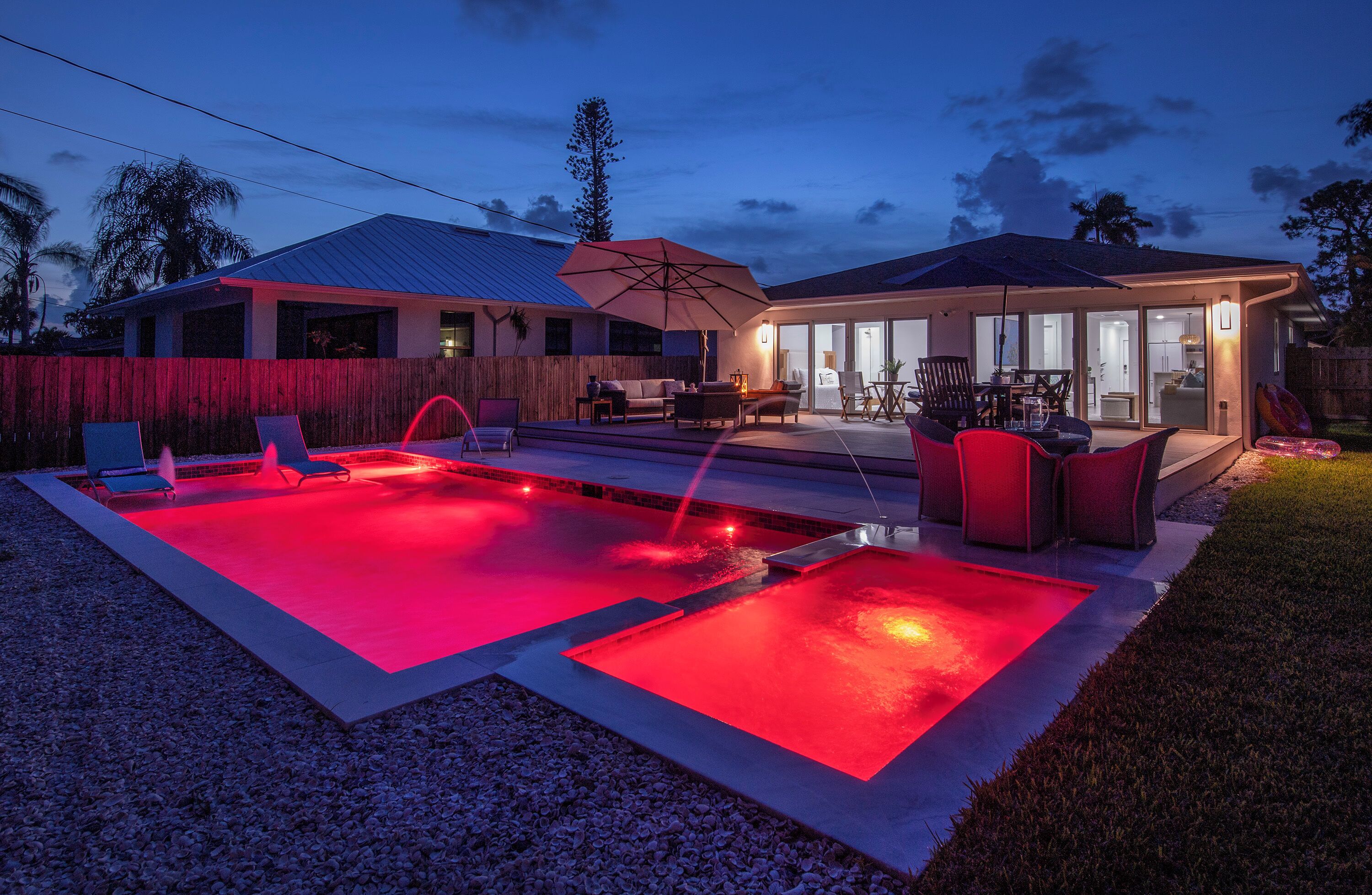 A backyard with a swimming pool, outdoor furniture, and a covered patio area.