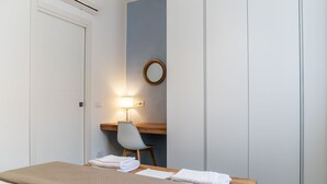 Ein Hotelzimmer mit einem Bett, einem Schreibtisch, einem Stuhl, einem runden Spiegel und einer Wand-Klimaanlage.