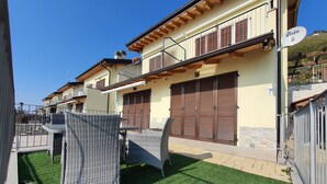 Un immeuble résidentiel doté d’un balcon, de mobilier d’extérieur et d’une pelouse bien entretenue.