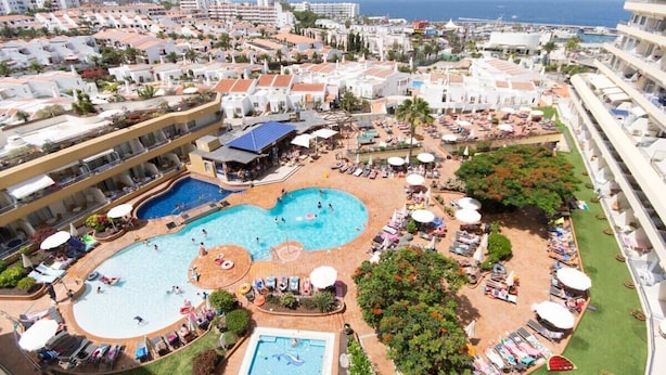 A resort with multiple swimming pools, sun loungers, and a view of the ocean.