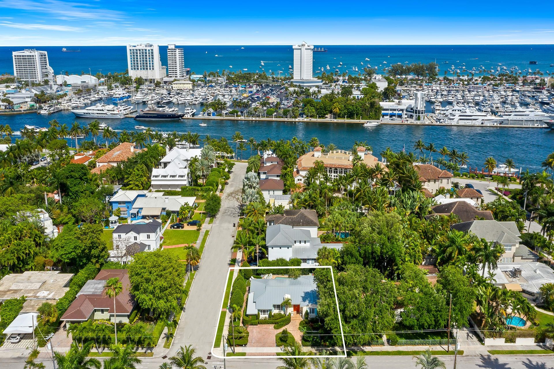 A coastal residential area with a marina filled with boats, a prominent white tower, and a clear view of the ocean.