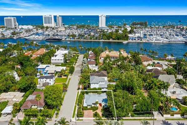Zona residencial costera con un puerto deportivo lleno de barcos, una imponente torre blanca y una vista despejada del océano.