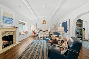 A spacious living room with a fireplace, dining area, and a view of the kitchen. - Palm Beacher - Heated Salt Water Pool (Fort Lauderdale)