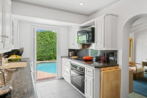 A modern kitchen with a built-in oven, a microwave, and a large window overlooking a swimming pool. - Palm Beacher - Heated Salt Water Pool (Fort Lauderdale)