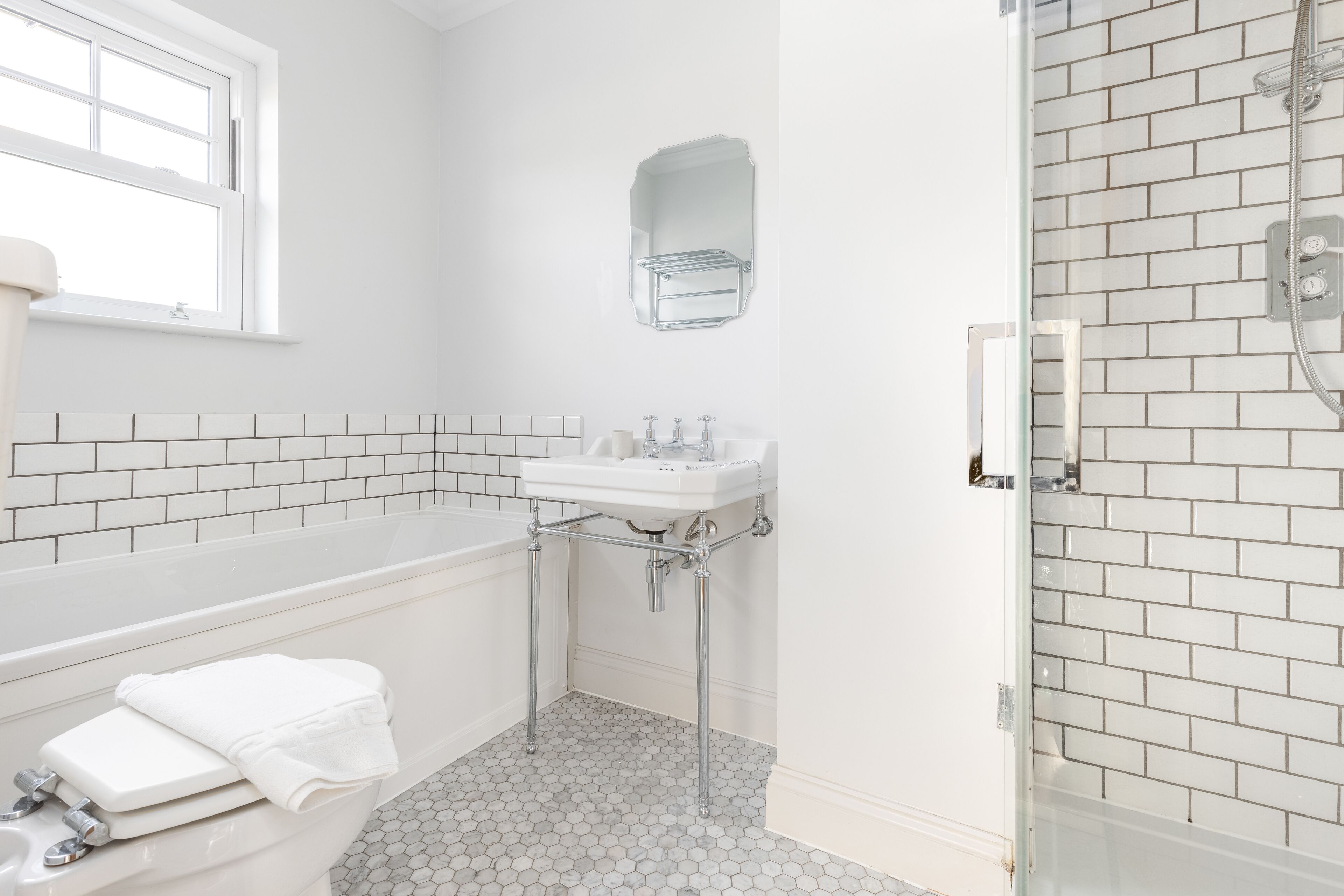 A bathroom with a white bathtub, a sink, and a shower area.
