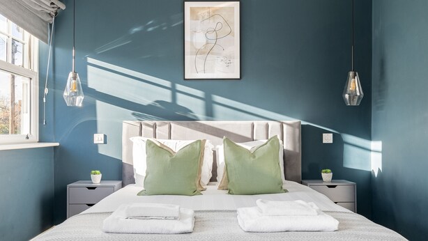 A bedroom with a bed, two nightstands, a headboard, and a wall-mounted artwork.