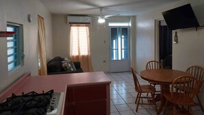 Un espacio habitable compacto con cocina, mesa de comedor y ventilador de techo.