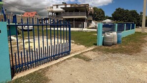 Un área residencial cerrada con un edificio de dos pisos, un patio cercado y un camino de grava.