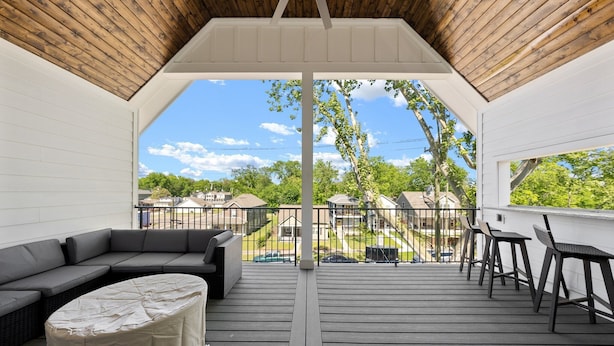 Une terrasse extérieure couverte, aménagée avec un canapé, une table ronde et deux chaises.