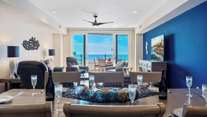 A modern living room with a view of the ocean, furnished with a dining table set for two, a sofa, and a chair. - Oceanfront/Ground Floor Unit/A/C/Parking/Guest Favorite (La Jolla)