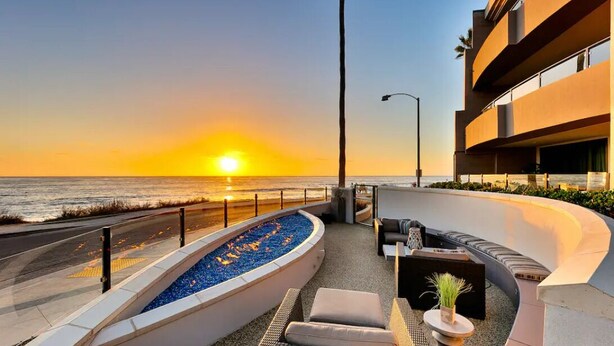 A sunset view from a balcony with outdoor seating and a pool. - Oceanfront/Ground Floor Unit/A/C/Parking/Guest Favorite (La Jolla)