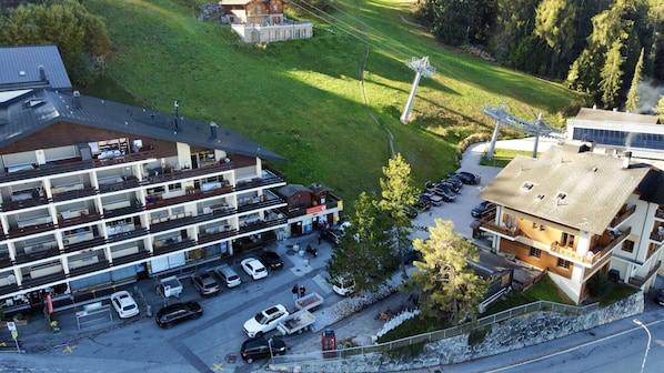 Ein mehrstöckiges Hotel mit Parkplatz, einem kleinen Garten und Blick auf die Umgebung.