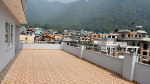 A balcony with patterned flooring, overlooking a densely packed urban area with various buildings and a mountainous backdrop. - Mount Star Homestay (Kathmandu)