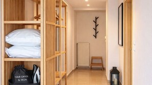 Un couloir avec une armoire en bois, un radiateur, une petite table et un luminaire suspendu.