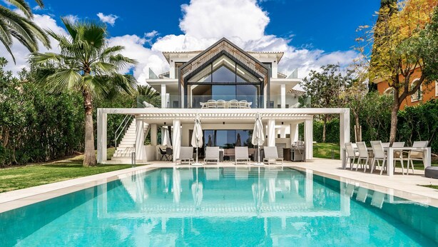 A modern house with a swimming pool, outdoor seating, and a covered patio area.