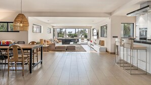 A spacious living area with a dining table, sofa, and kitchen area with a bar.