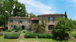A stone building with multiple windows and a garden in front.