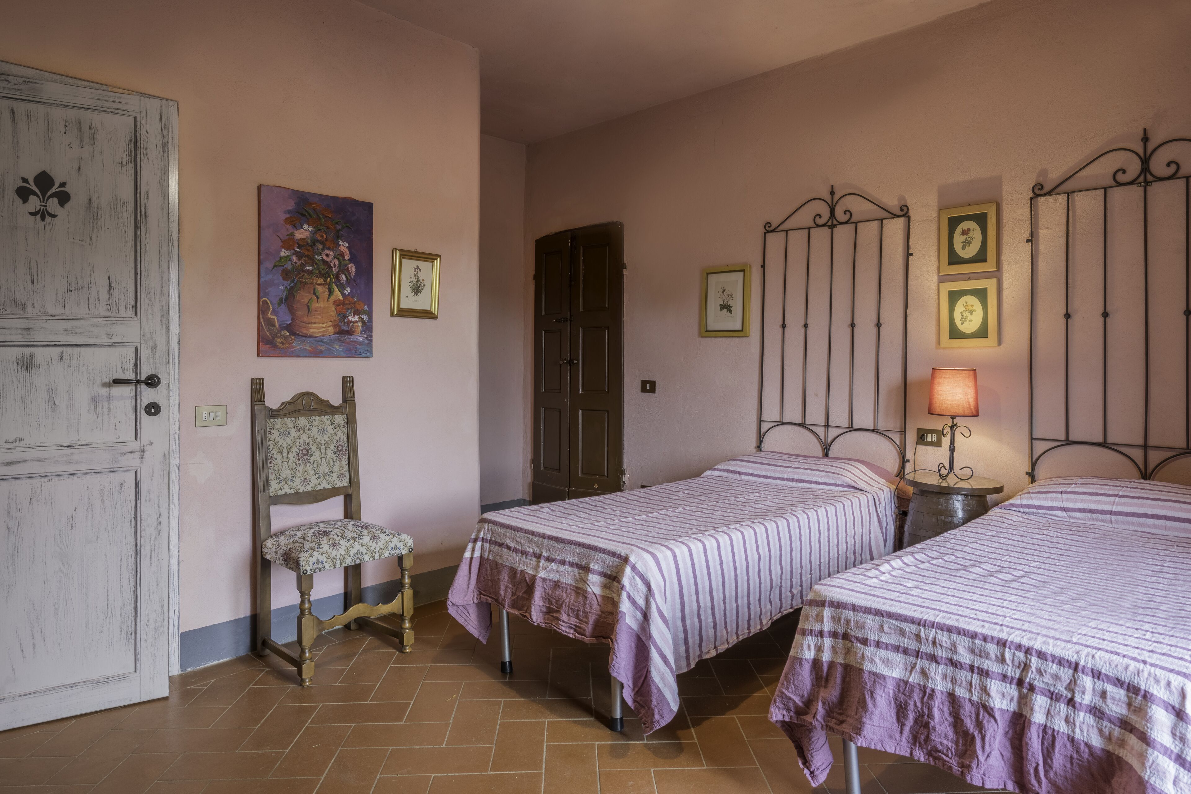 Une chambre avec deux lits, une chaise, une porte et des éléments décoratifs sur les murs.
