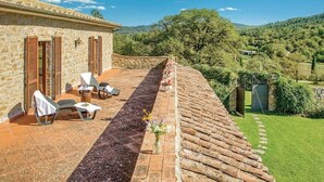 A stone building with a terrace, outdoor seating, and a view of the countryside.