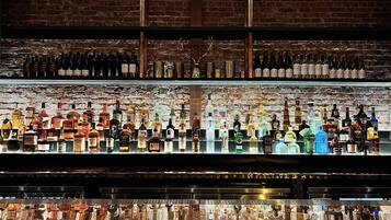 Un bar doté de plusieurs étagères remplies de bouteilles d’alcool et d’un comptoir avec un distributeur de boissons.