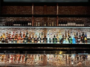 A bar with multiple shelves of liquor bottles and a bar counter with a drink dispenser.