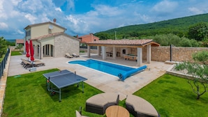 Una piscina con solarium, lettini e tavolo da ping pong.