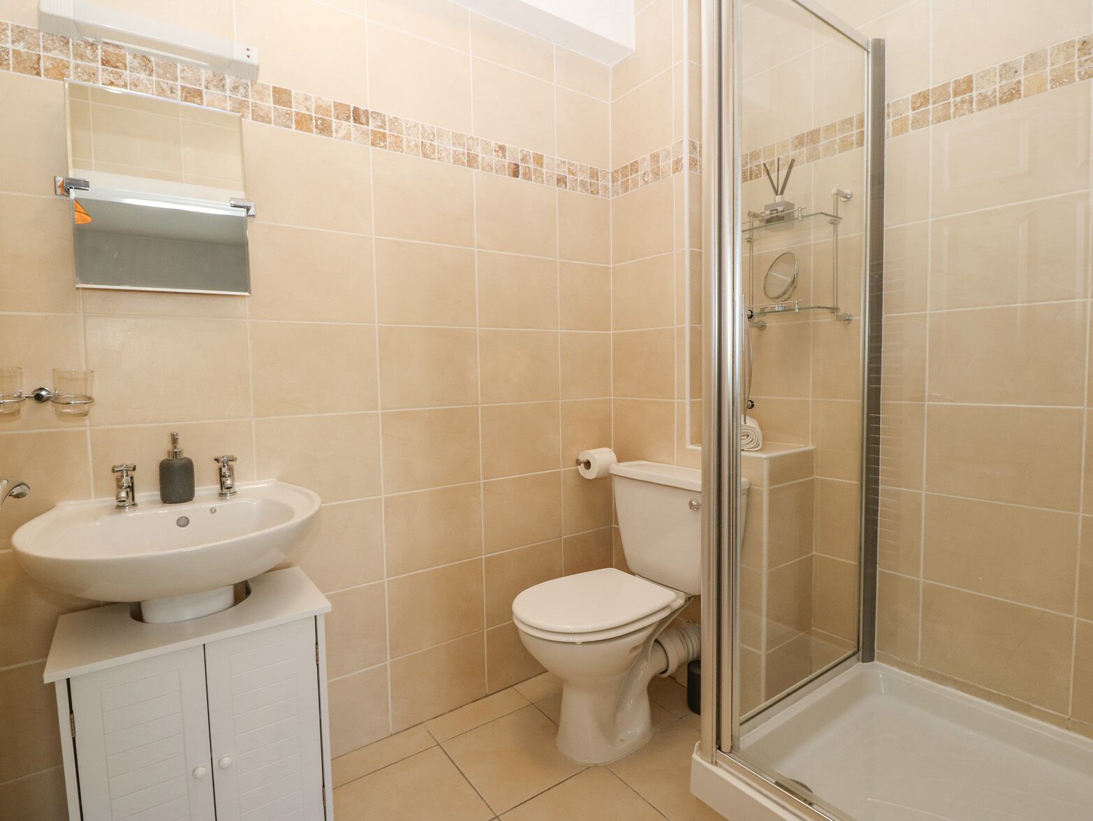 A bathroom with a sink, toilet, and glass-enclosed shower.