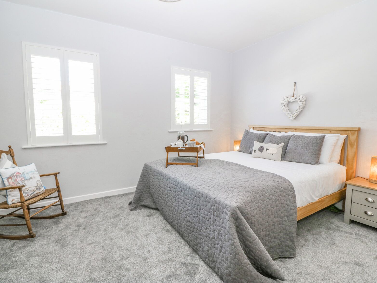 A bedroom with a bed, nightstands, a rocking chair, and a window.