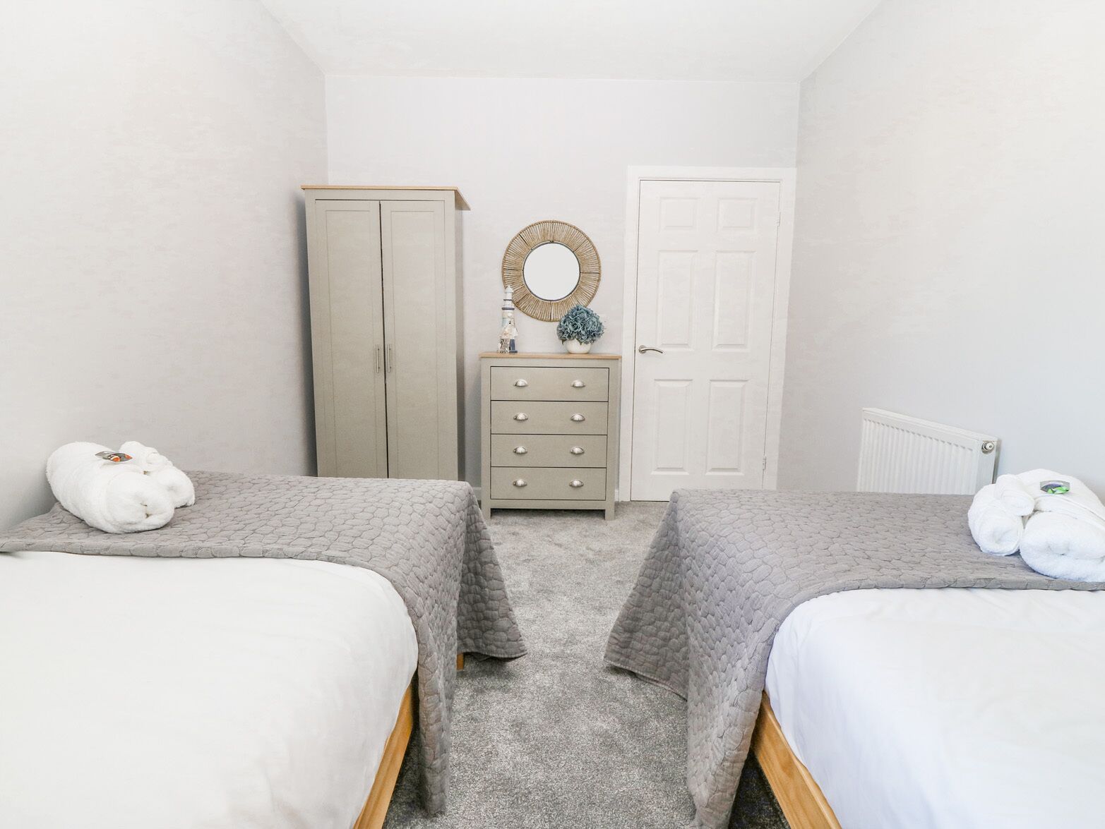 Une chambre avec deux lits, une armoire, une commode et un miroir.