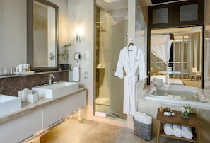 Bathroom features a large mirror, two sinks, and a bathtub, with a shower area accessible through a glass door.
