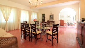 A dining area with a glass table surrounded by chairs, a chandelier, and a view through an archway to a living room. - Villa The Park - Imperial Rome (Forte dei Marmi)