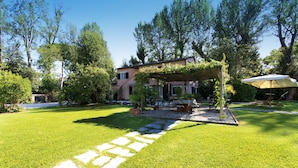 A well-maintained garden with a stone pathway leading to a covered seating area. - Villa The Park - Imperial Rome (Forte dei Marmi)