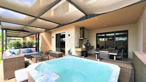 Un espace extérieur abrité comprenant un jacuzzi, des sièges et un barbecue.
