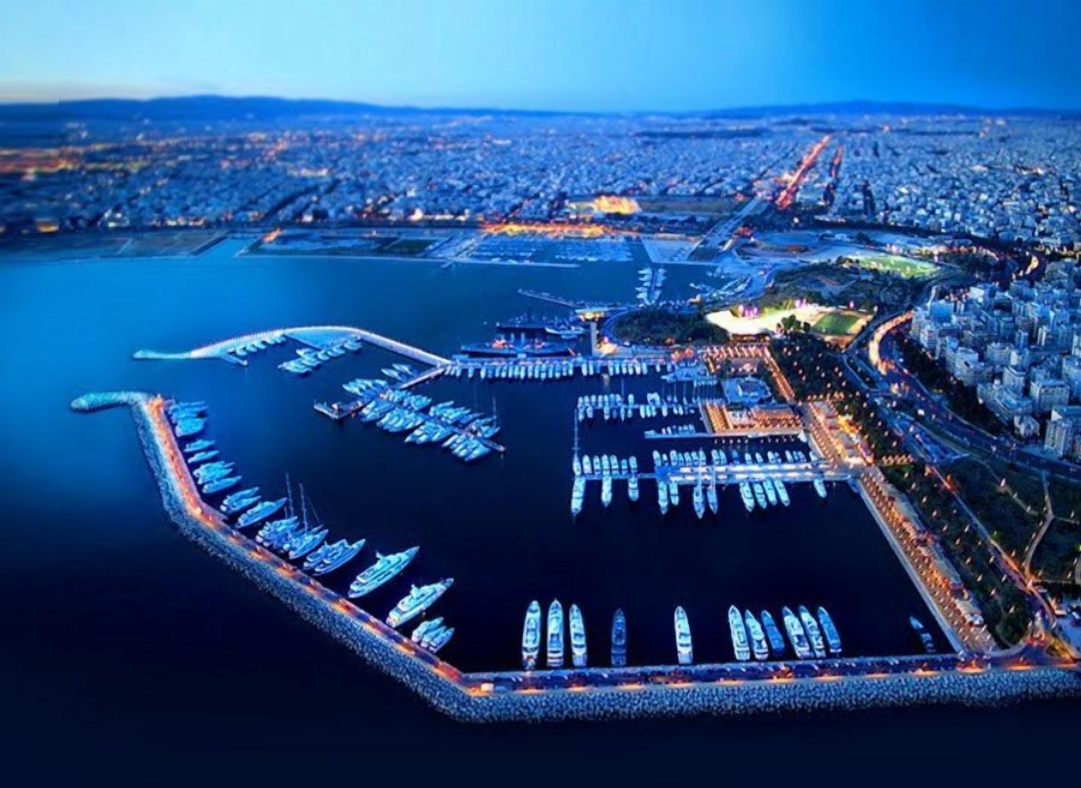 Vista aerea di una marina con numerosi pontili e imbarcazioni, circondata da un paesaggio urbano.