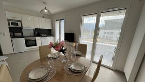 Una cocina moderna con armarios blancos, un microondas y una estufa. Hay una mesa de comedor dispuesta con platos, vasos y un florero con flores.